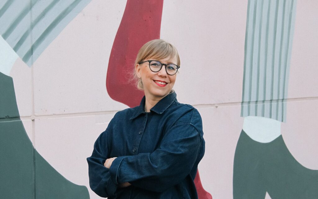 ILMEen uusi työntekijä Maiju Leppänen hymyilemässä muraalin edustalla